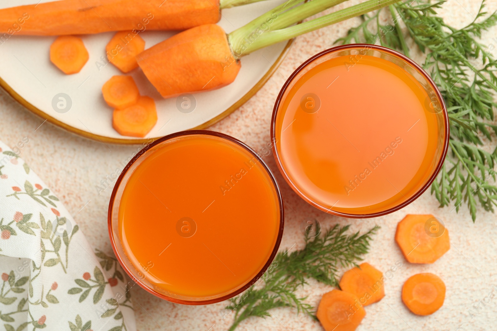 Photo of Healthy carrot juice in glasses and fresh vegetables on color textured table, top view