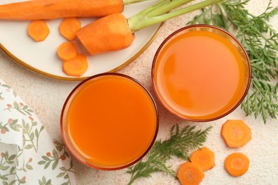 Photo of Healthy carrot juice in glasses and fresh vegetables on color textured table, top view