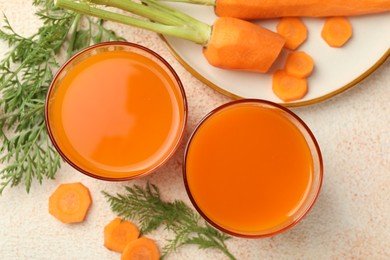 Photo of Healthy carrot juice in glasses and fresh vegetables on color textured table, top view