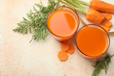 Photo of Healthy carrot juice in glasses and fresh vegetables on color textured table, above view. Space for text