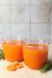 Photo of Healthy carrot juice in glasses and fresh vegetable on color textured table