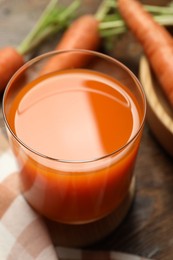 Photo of Healthy carrot juice in glass and fresh vegetables on table, closeup
