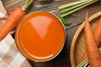 Photo of Healthy carrot juice in glass and fresh vegetables on wooden table, top view