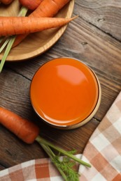 Photo of Healthy carrot juice in glass and fresh vegetables on wooden table, top view