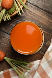 Photo of Healthy carrot juice in glass and fresh vegetables on wooden table, top view