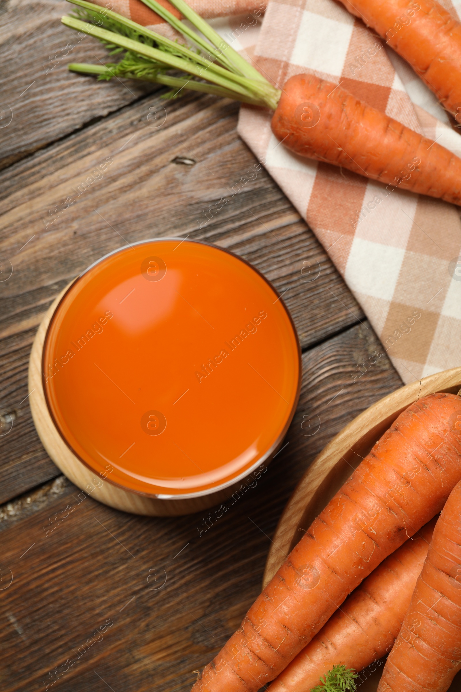 Photo of Healthy carrot juice in glass and fresh vegetables on wooden table, top view