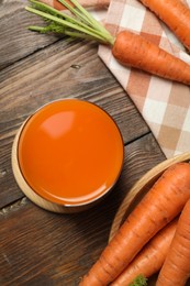 Photo of Healthy carrot juice in glass and fresh vegetables on wooden table, top view