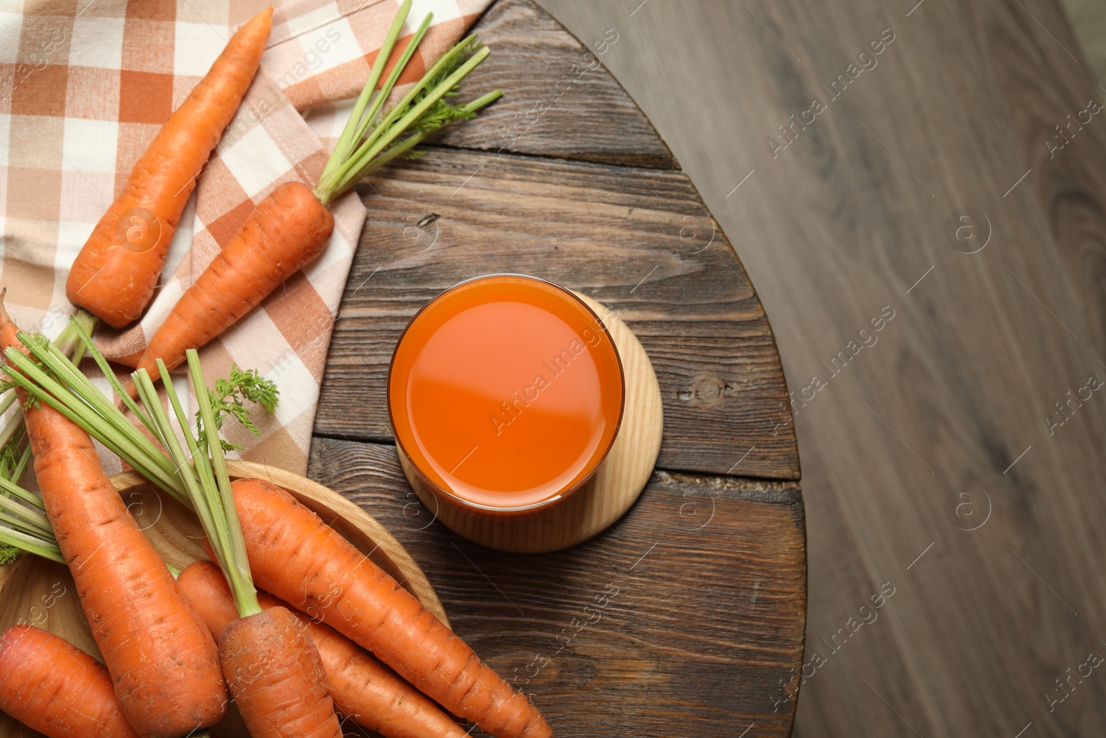 Photo of Healthy carrot juice in glass and fresh vegetables on wooden table, top view. Space for text