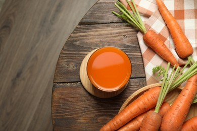 Photo of Healthy carrot juice in glass and fresh vegetables on wooden table, top view. Space for text