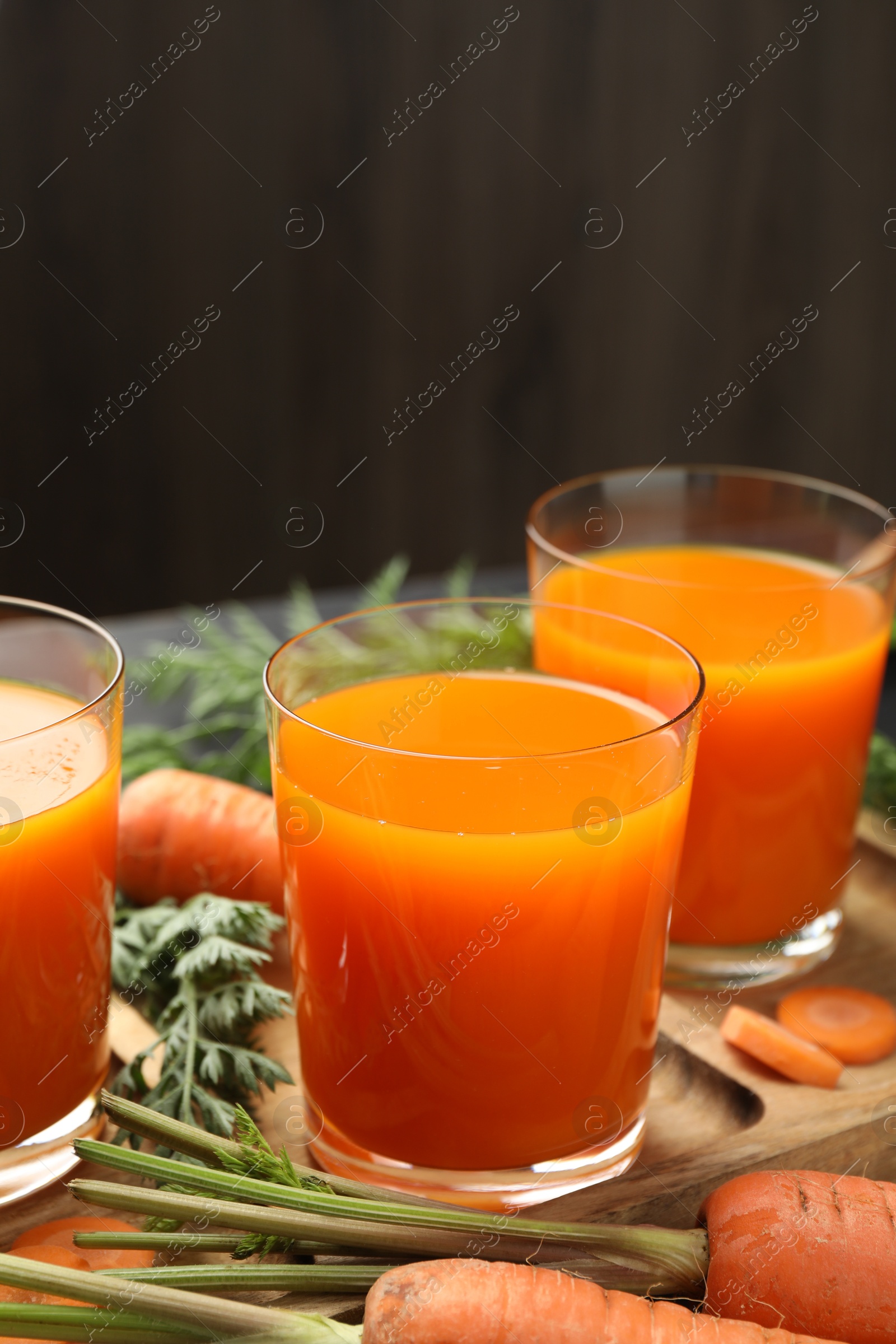 Photo of Healthy carrot juice in glasses and fresh vegetables on table