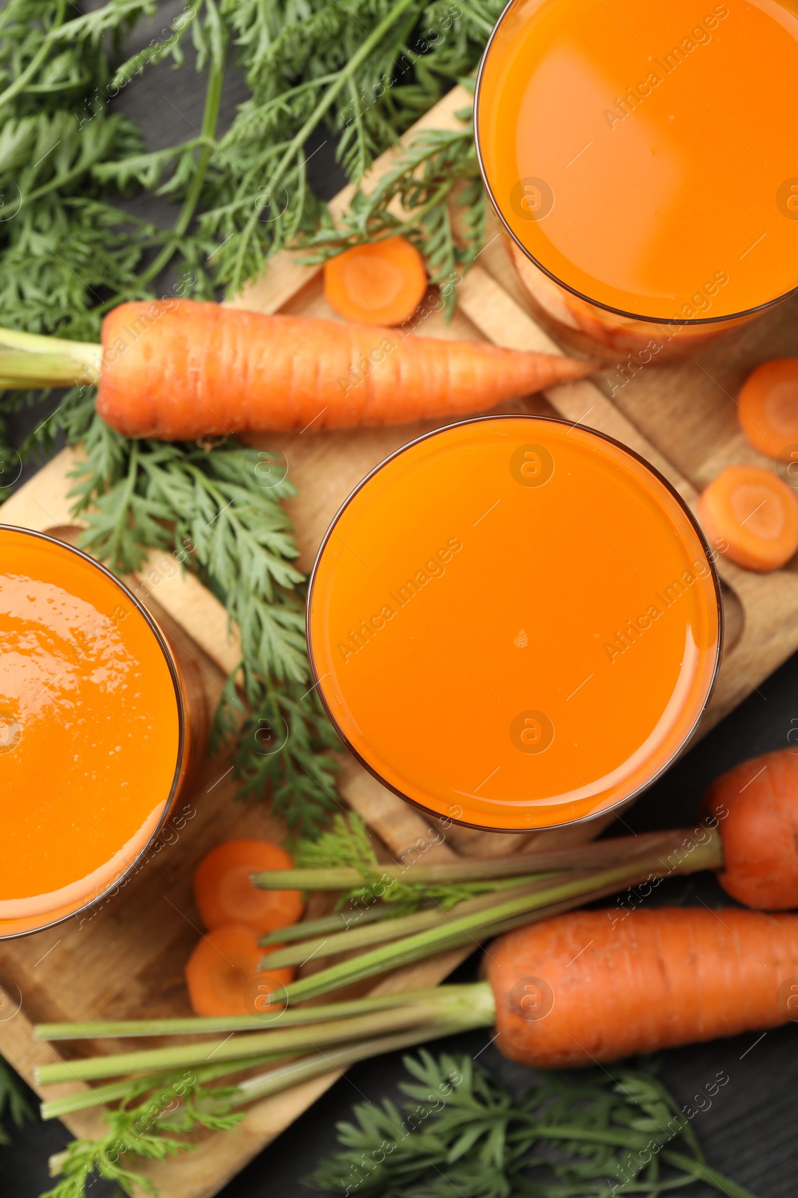 Photo of Healthy carrot juice in glasses and fresh vegetables on table, top view