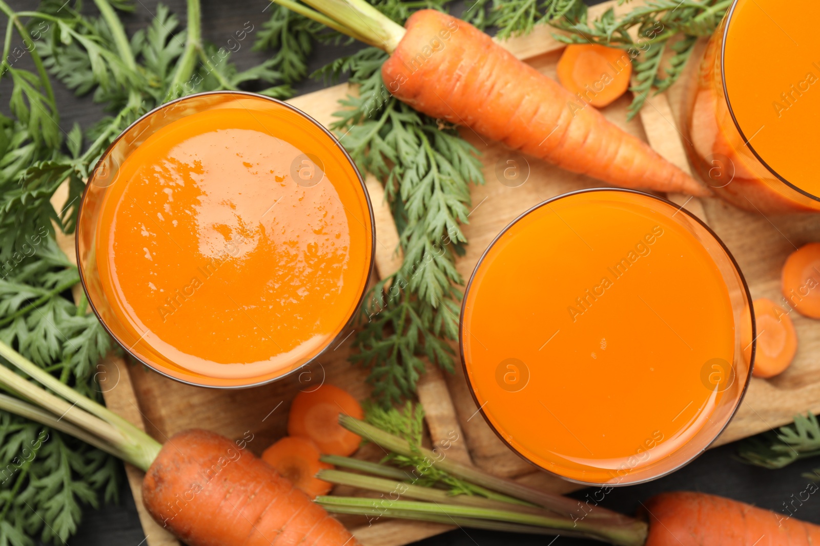 Photo of Healthy carrot juice in glasses and fresh vegetables on table, top view