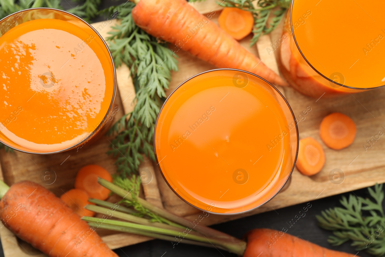 Photo of Healthy carrot juice in glasses and fresh vegetables on table, top view