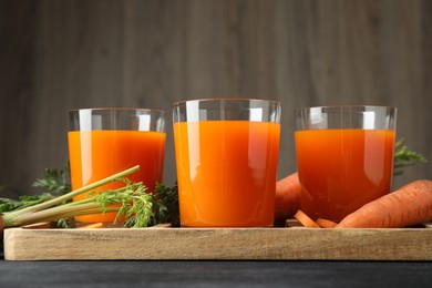 Photo of Healthy carrot juice in glasses and fresh vegetables on table