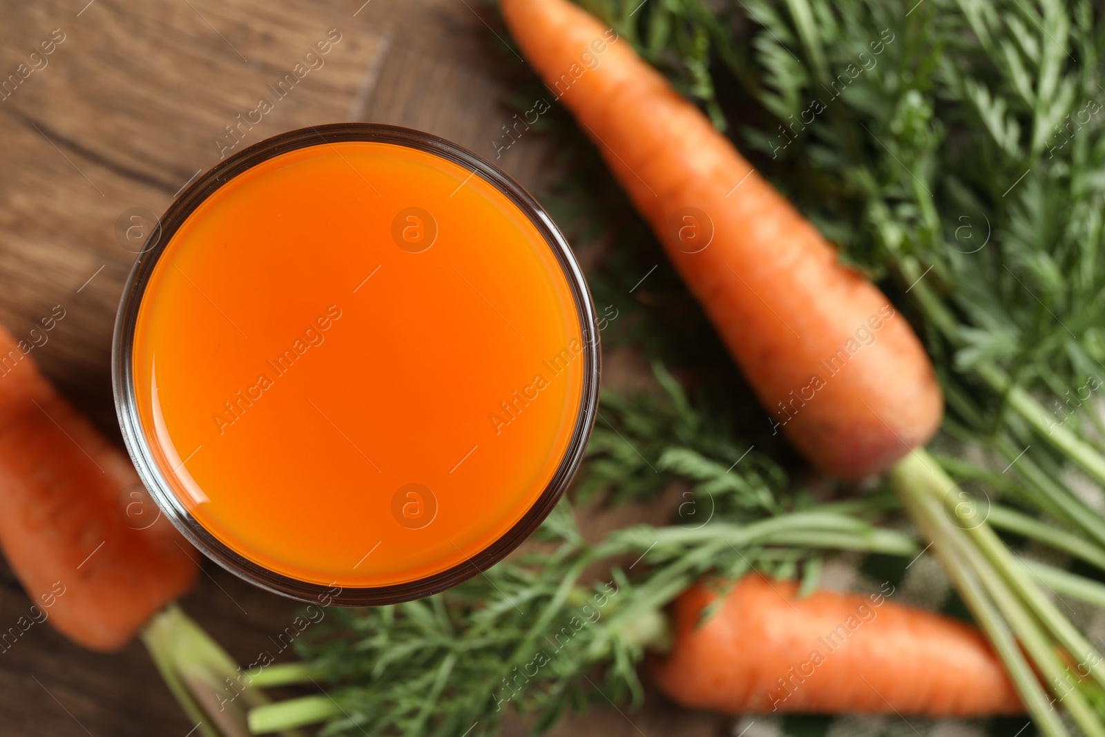 Photo of Healthy carrot juice in glass and fresh vegetables on table, top view