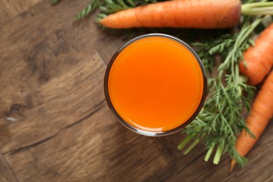 Healthy carrot juice in glass and fresh vegetables on wooden table, top view. Space for text