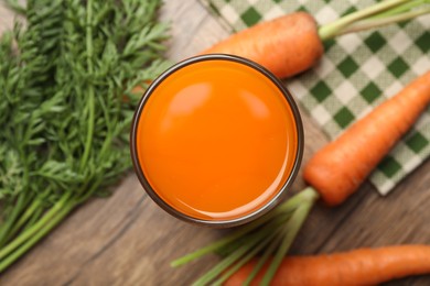 Photo of Healthy carrot juice in glass and fresh vegetables on wooden table, top view