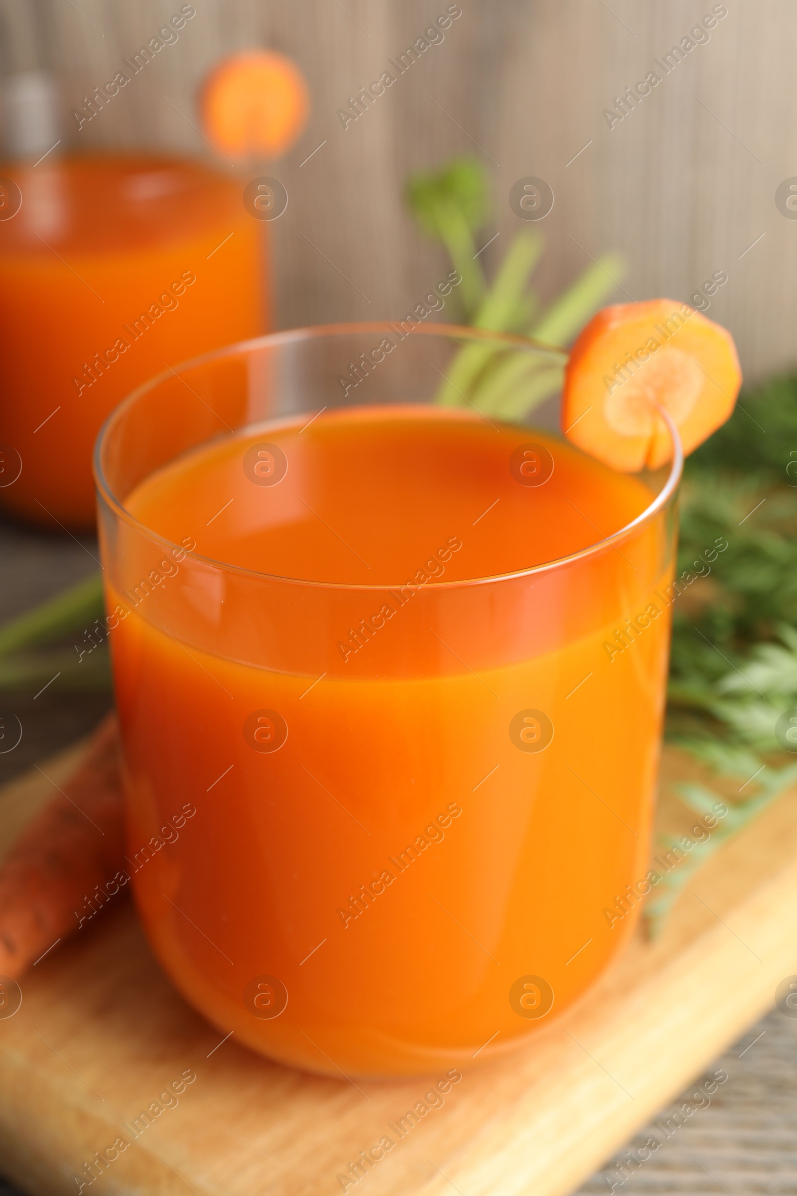 Photo of Healthy carrot juice in glass and fresh vegetable on table, closeup