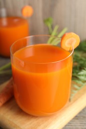 Photo of Healthy carrot juice in glass and fresh vegetable on table, closeup