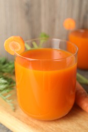 Photo of Healthy carrot juice in glass and fresh vegetable on table, closeup