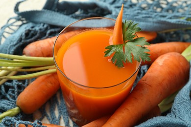 Healthy juice in glass and fresh carrot on table, closeup