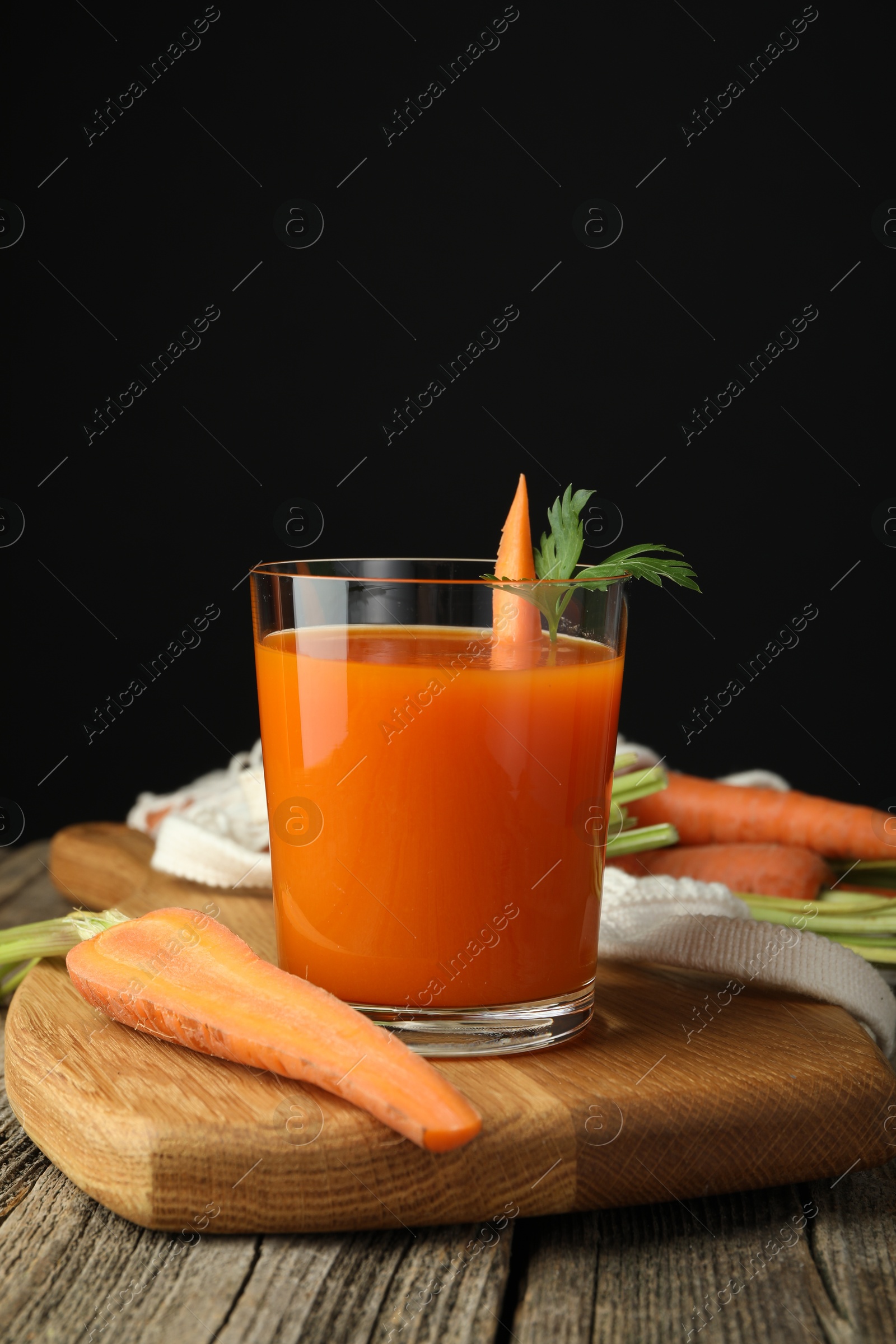 Photo of Healthy juice in glass and fresh carrot on wooden table