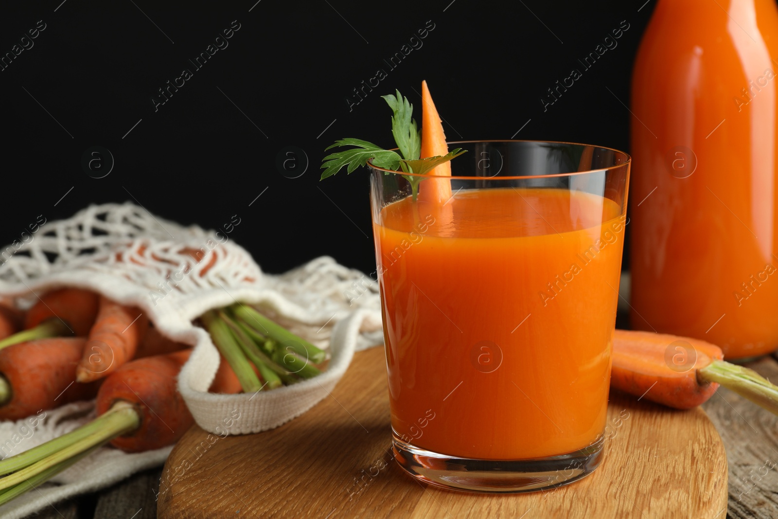 Photo of Healthy juice and fresh carrot on wooden table