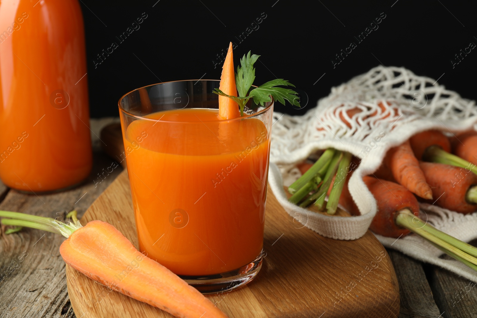 Photo of Healthy juice and fresh carrot on wooden table