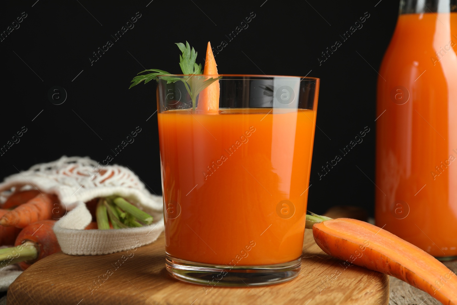 Photo of Healthy juice and fresh carrot on wooden table, closeup