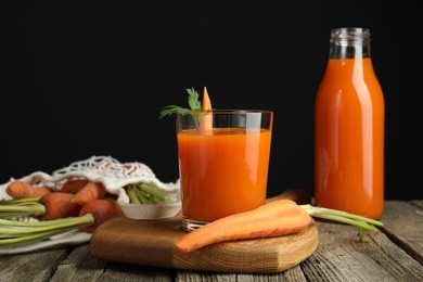 Photo of Healthy juice and fresh carrot on wooden table