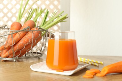 Healthy juice in glass and fresh carrot on wooden table