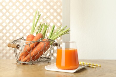 Healthy juice in glass and fresh carrot on wooden table