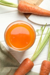 Photo of Healthy juice in glass and fresh carrot on white wooden table, flat lay