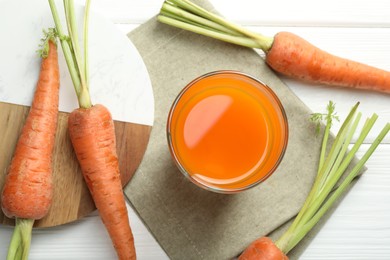 Photo of Healthy juice in glass and fresh carrot on white wooden table, flat lay