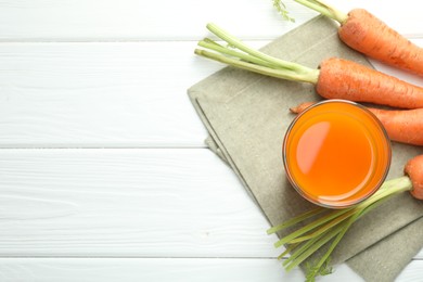 Photo of Healthy juice in glass and fresh carrot on white wooden table, flat lay. Space for text