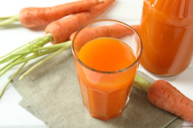 Healthy juice and fresh carrot on white wooden table