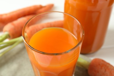 Photo of Healthy juice and fresh carrot on white wooden table, closeup