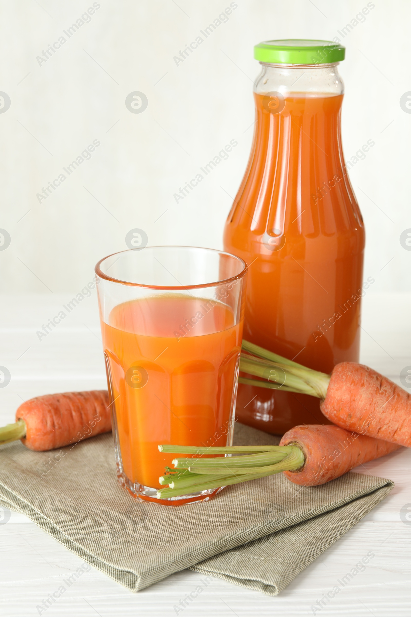 Photo of Healthy juice and fresh carrot on white wooden table