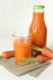 Photo of Healthy juice and fresh carrot on white wooden table