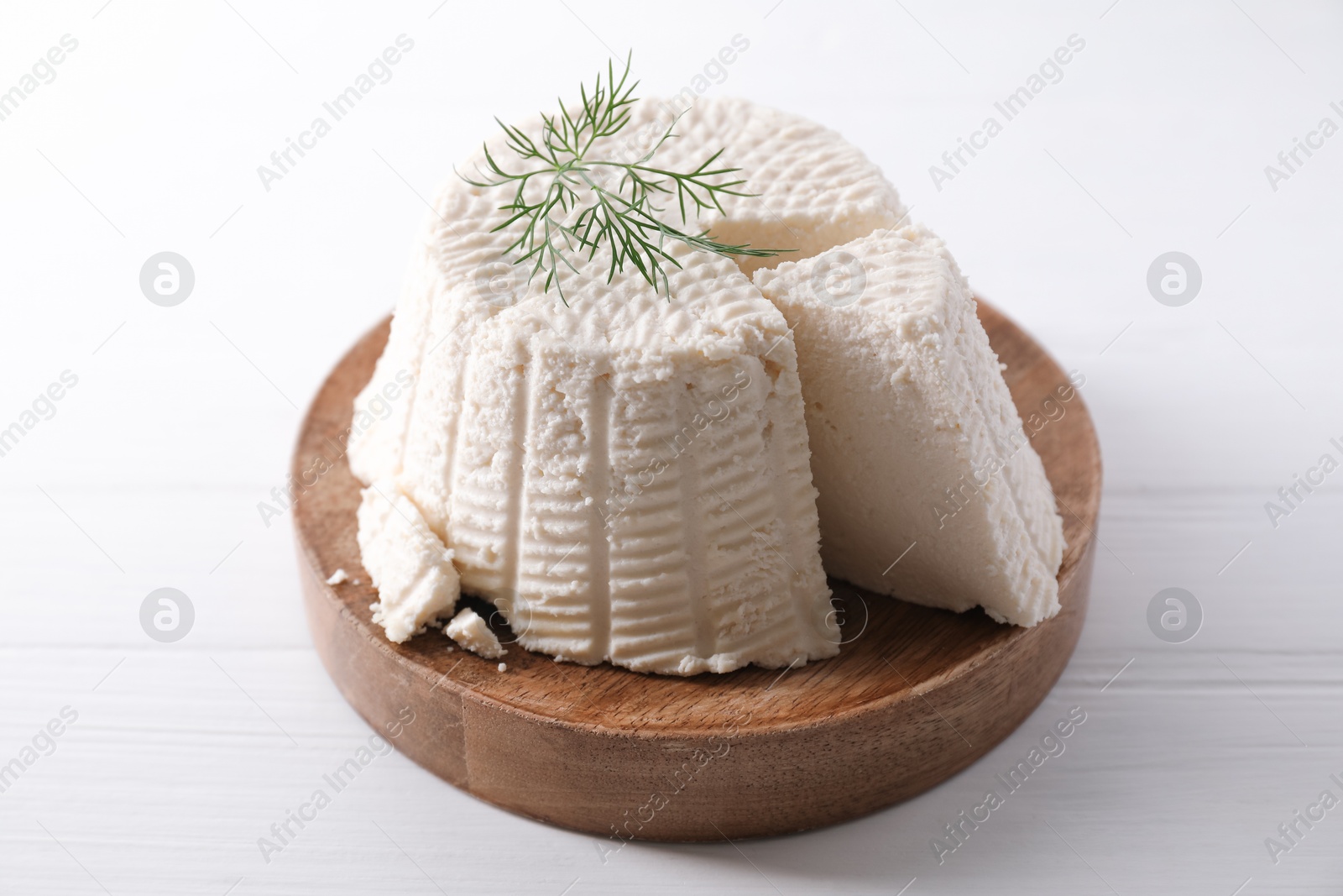 Photo of Fresh cut ricotta (cream cheese) with dill on white wooden table