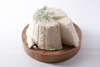 Fresh cut ricotta (cream cheese) with dill on white wooden table