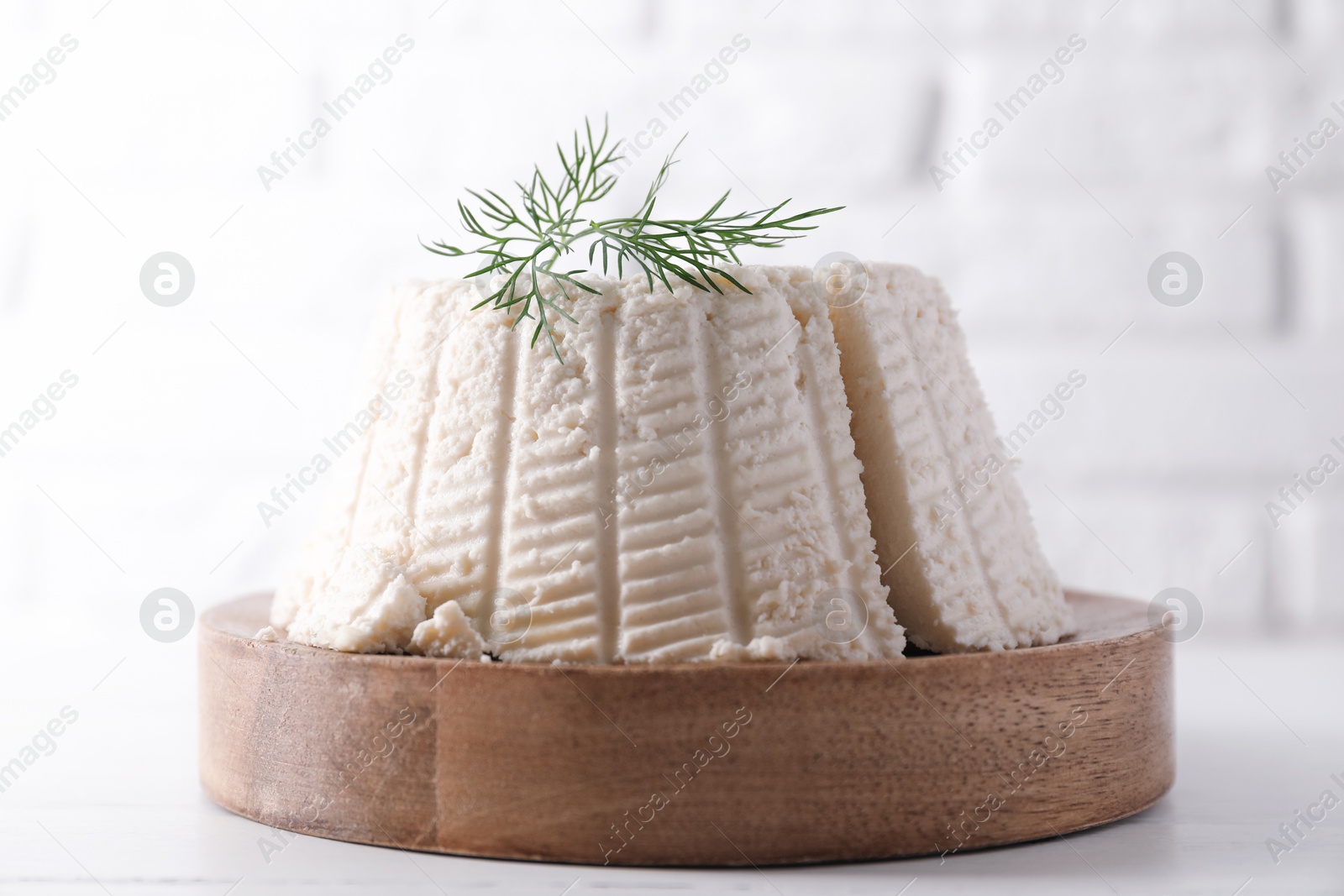 Photo of Fresh cut ricotta (cream cheese) with dill on white table, closeup