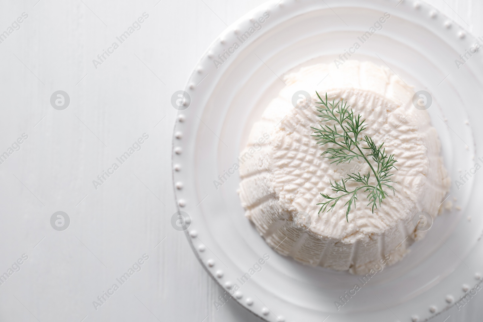 Photo of Fresh ricotta (cream cheese) with dill on white wooden table, top view. Space for text