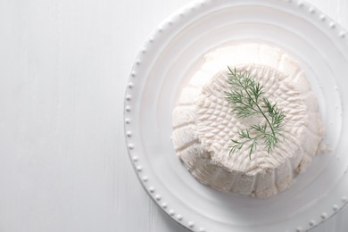 Fresh ricotta (cream cheese) with dill on white wooden table, top view. Space for text