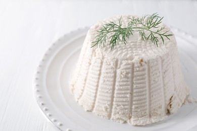 Fresh ricotta (cream cheese) with dill on white table, closeup