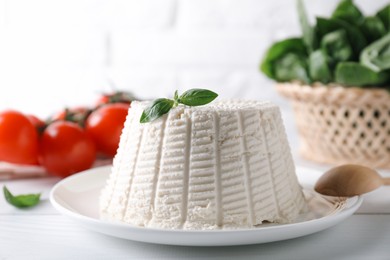 Photo of Fresh ricotta (cream cheese) with basil on white table, closeup