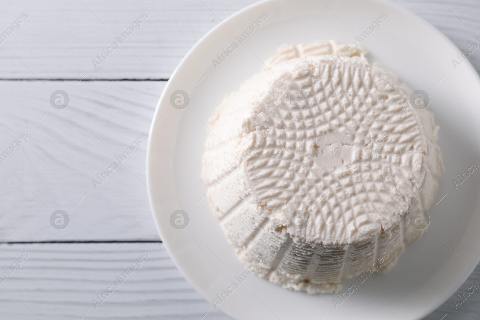 Photo of Fresh ricotta (cream cheese) on white wooden table, top view. Space for text