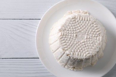 Fresh ricotta (cream cheese) on white wooden table, top view. Space for text