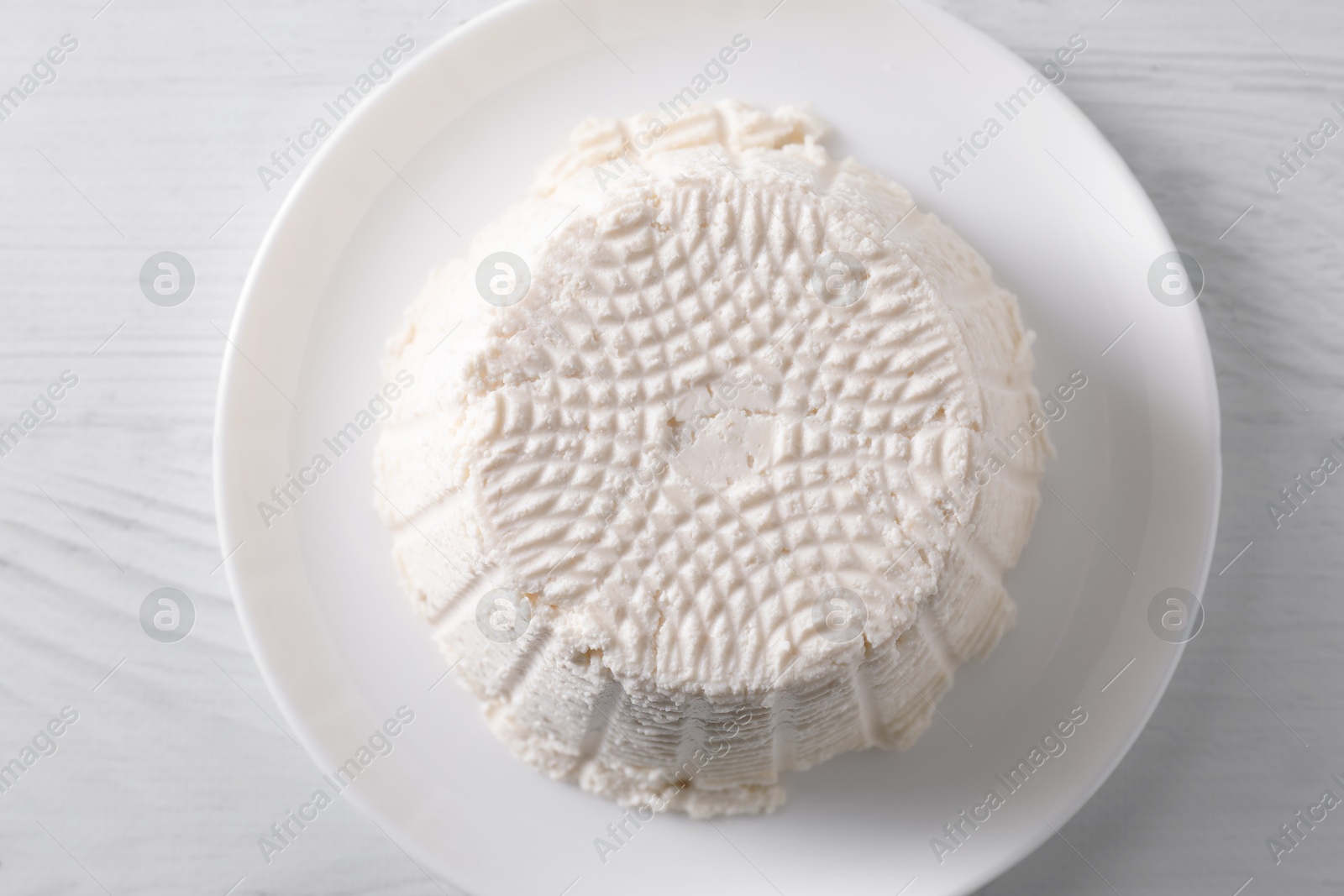 Photo of Fresh ricotta (cream cheese) on white wooden table, top view