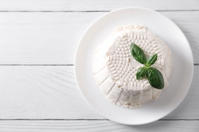 Fresh ricotta (cream cheese) and basil on white wooden table, top view. Space for text